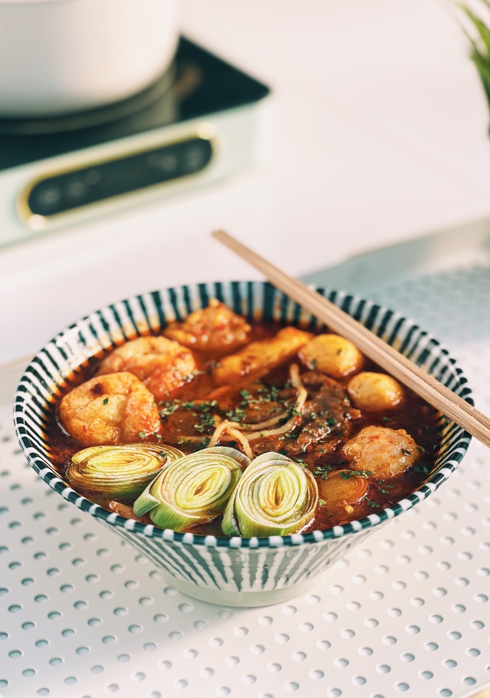A bowl of spicy beef noodles with leek and chopsticks