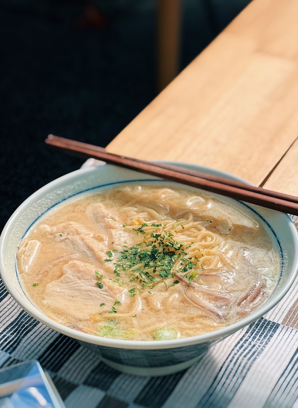 A bowl of creamy chicken ramen with chopsticks resting on the rim