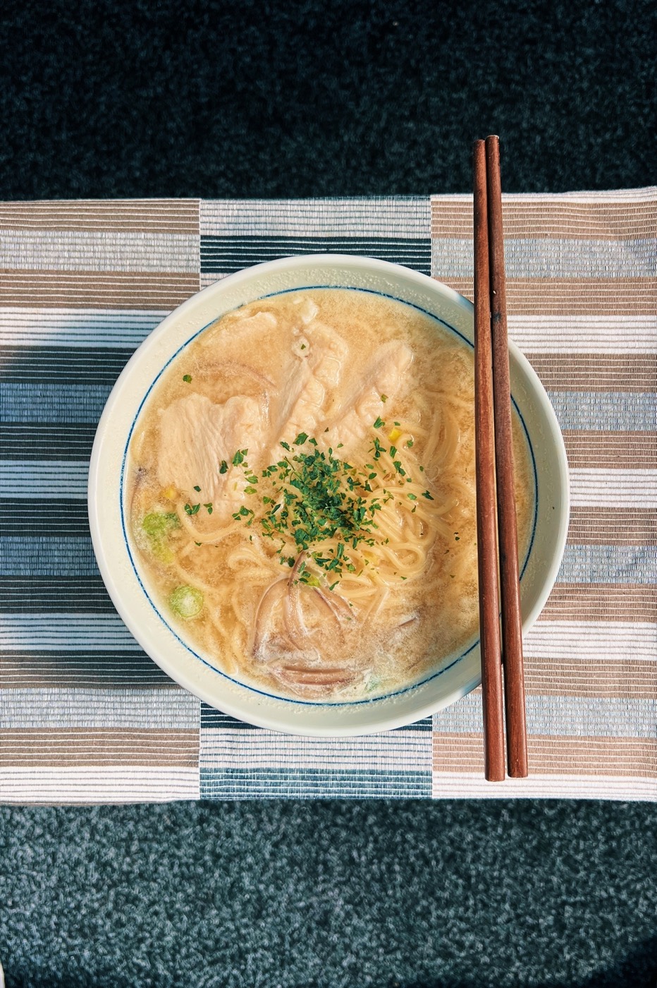 A bowl of creamy chicken ramen seen from above with chopsticks